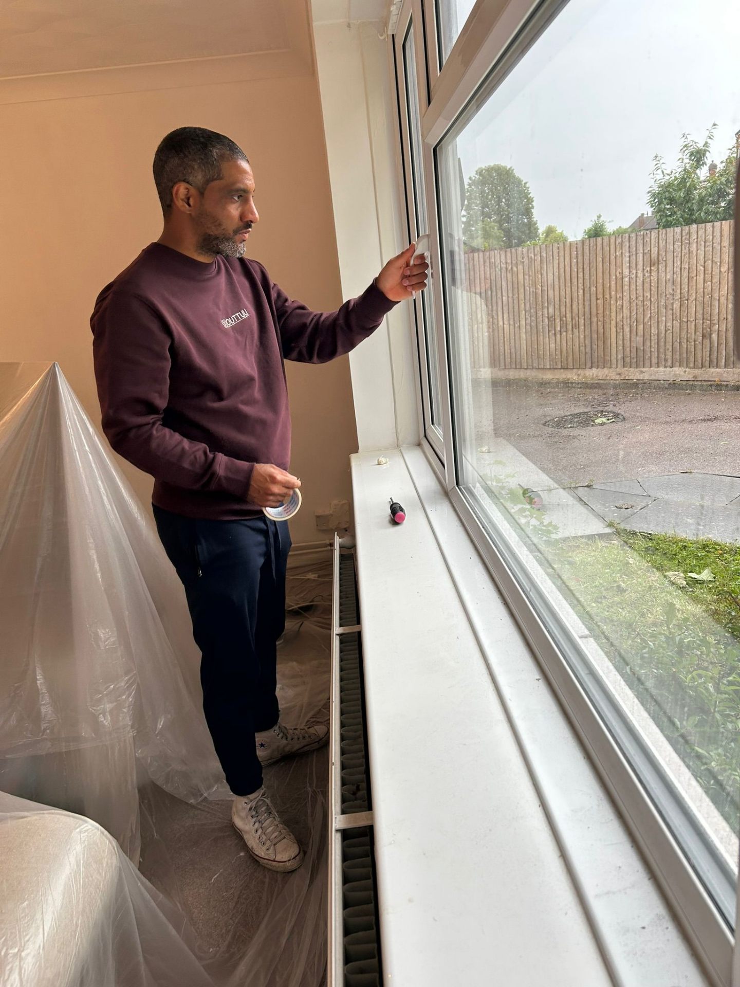 Ricky carefully taping skirting boards during decorating preparation in a Bedfordshire village home.
