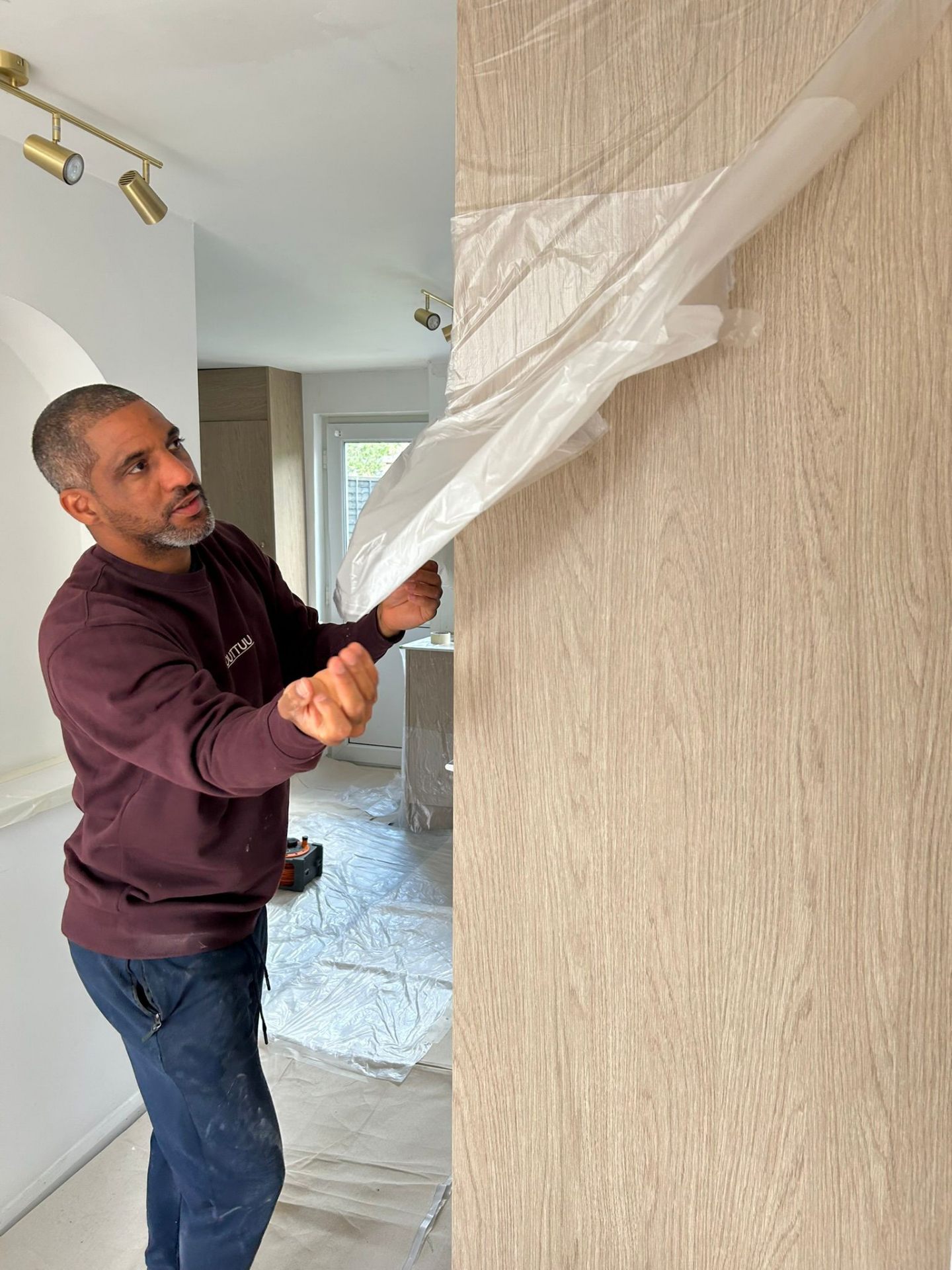Ricky from OUTTUU hanging protective sheeting during prep work in Bedford