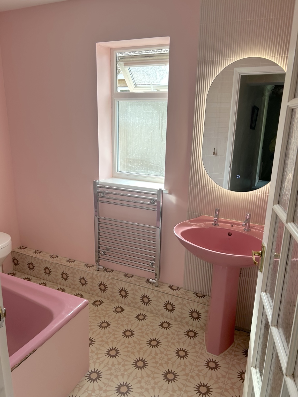 Refreshed bathroom in Sharnbrook with soft pink walls, a heated towel rail and patterned floor tiles.