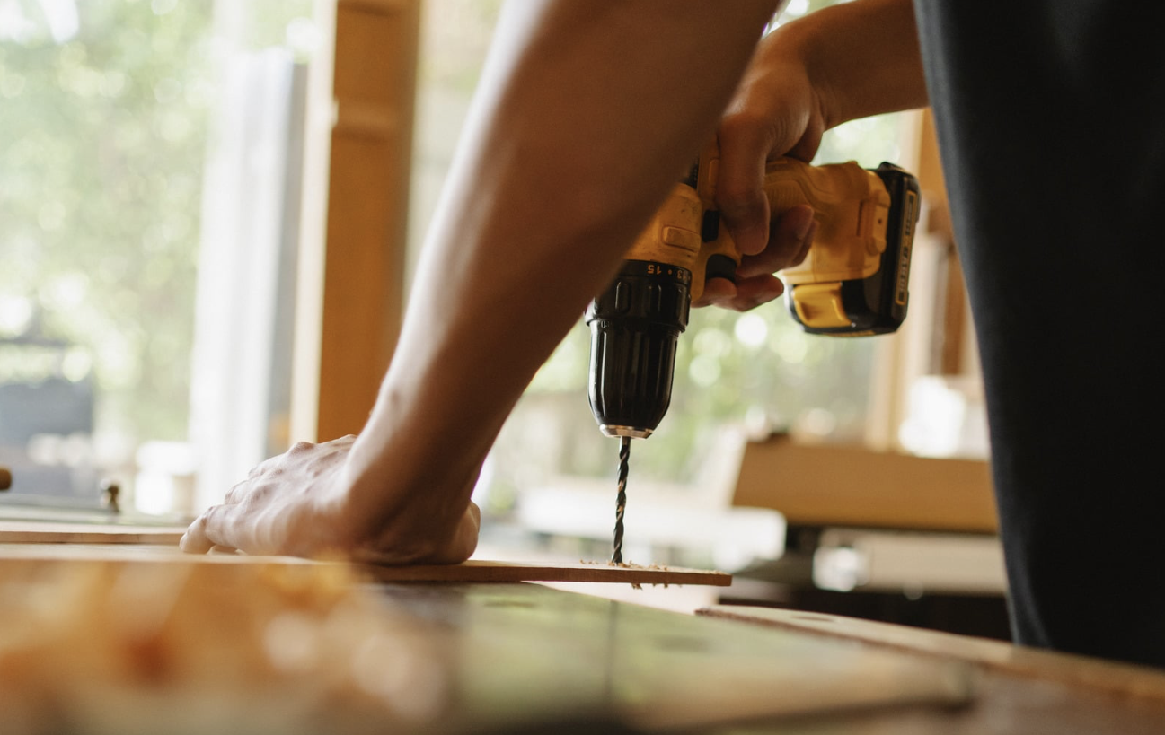 Close-up of a cordless drill being used on a timber board.