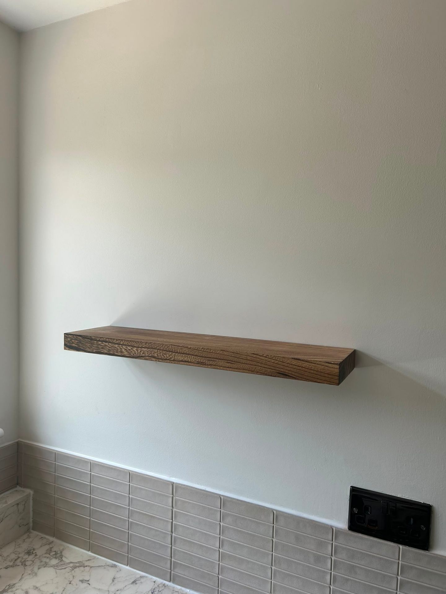 Solid wood floating shelf installed above tiled splashback in a Bedford home.