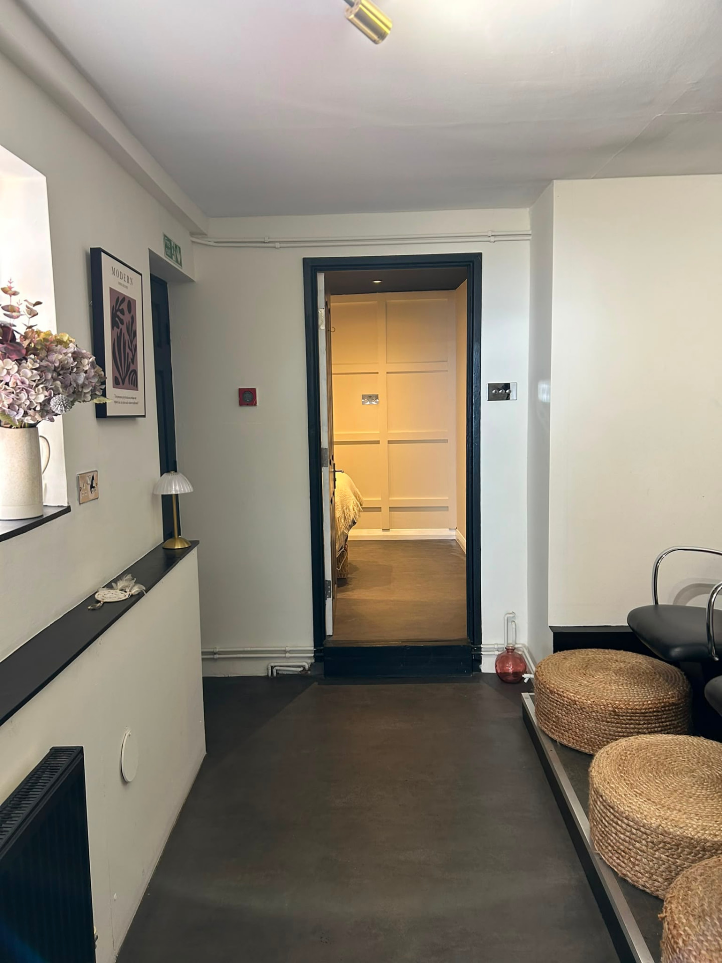 Refreshed salon corridor and treatment room in Bedford with deep navy doorway, panelled walls and warm lighting.