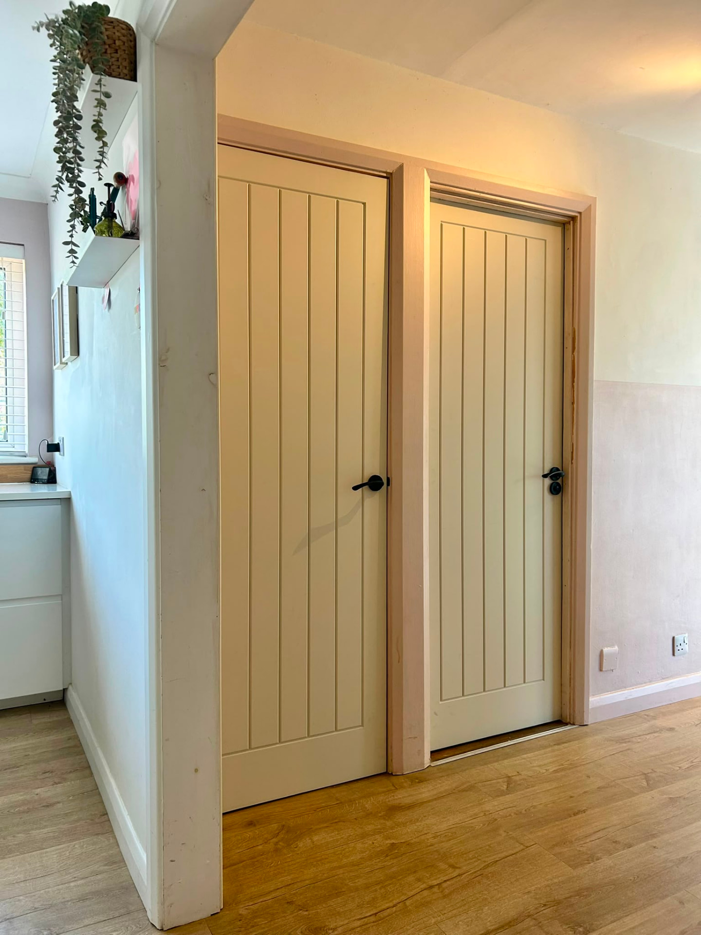 Two newly fitted cream internal doors with black handles and oak frames in a Felmersham home.
