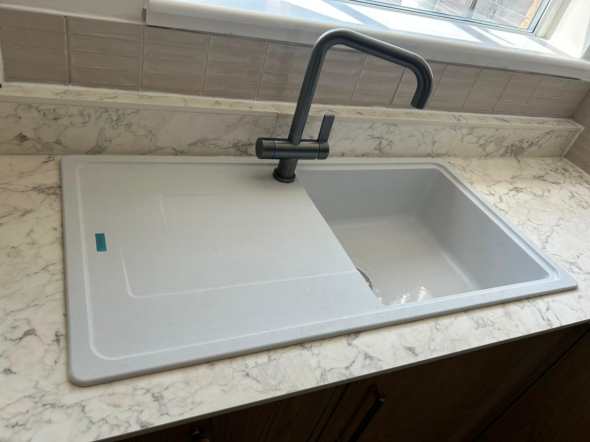 New composite kitchen sink and matte black mixer tap fitted on a marble worktop in Bedford.